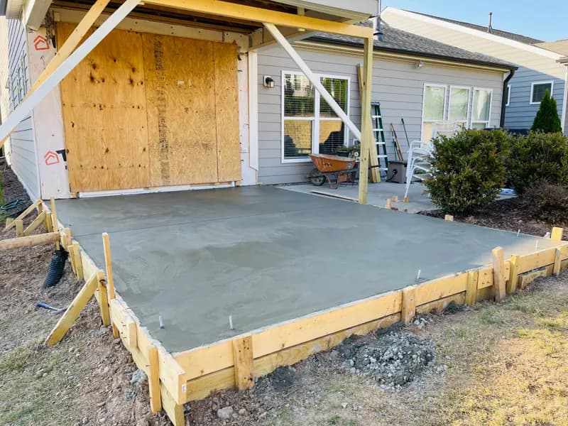 Freshly poured concrete patio slab behind a home