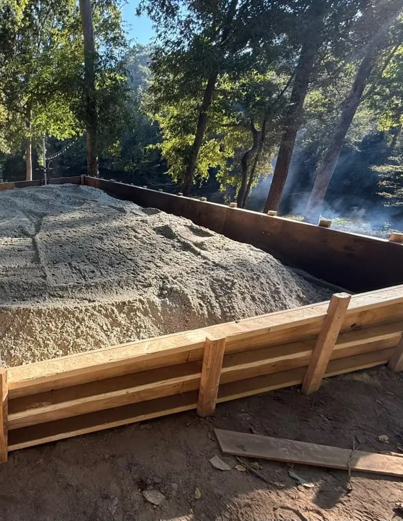 Gravel base inside wooden forms on a wooded residential lot