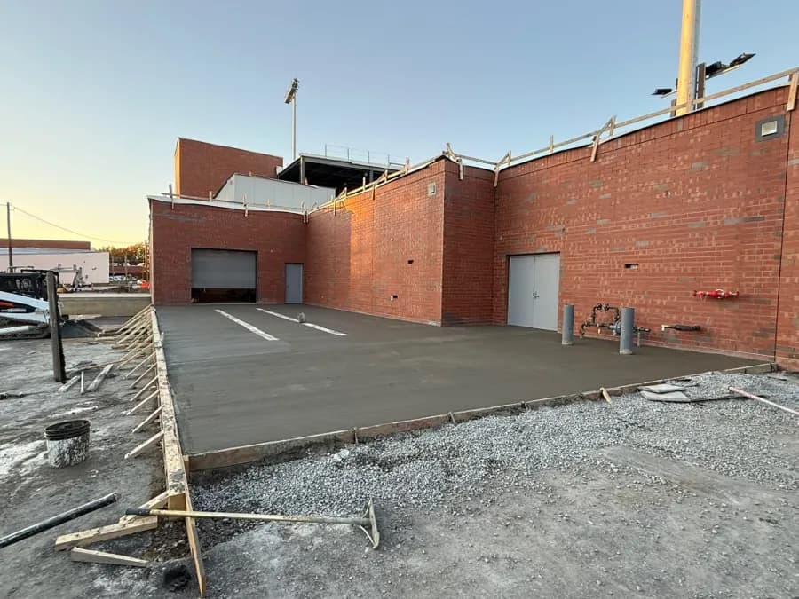 Freshly poured commercial slab with formwork behind a brick building